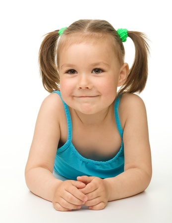Portrait of a cute happy little girl laying on floor, isolated over whiteの写真素材