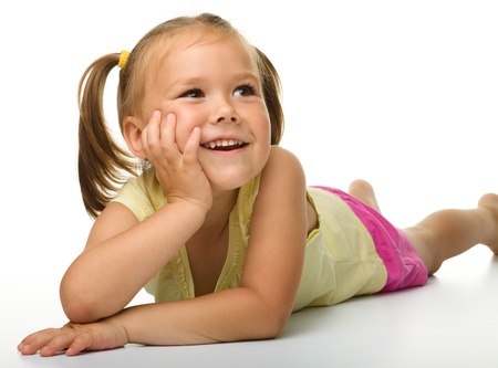 Portrait of a cute happy little girl laying on floor, isolated over whiteの写真素材