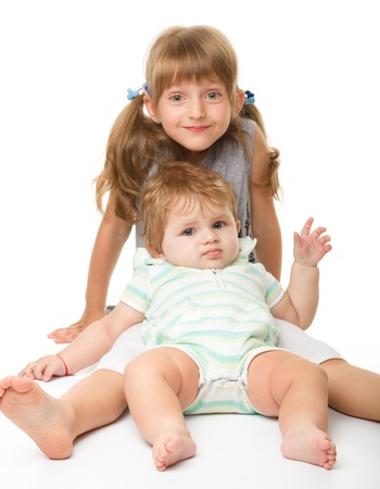 Two children (a girl and a boy) are having fun while sitting on floor, isolated over whiteの写真素材
