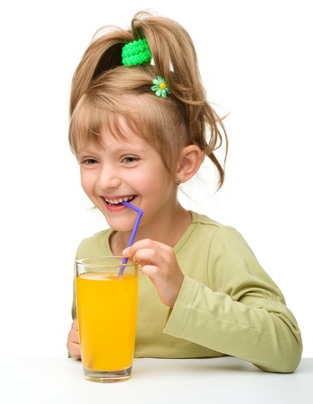 Cute little girl is drinking orange juice from one glass using straw, isolated over whiteの写真素材