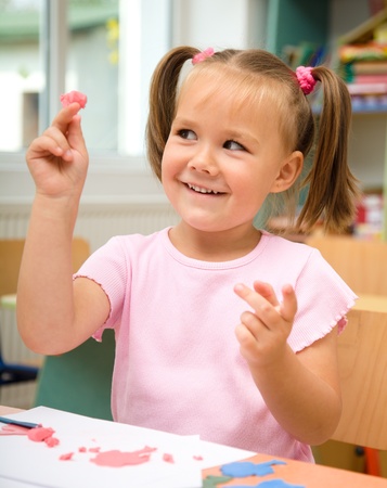 Little girl is playing with plasticine in preschoolの写真素材