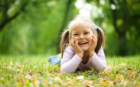 Cute little girl is playing with leaves in autumn parkの写真素材
