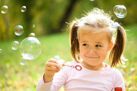 Cute little girl is blowing a soap bubblesの写真素材