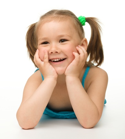 Portrait of a cute happy little girl laying on floor, isolated over whiteの写真素材