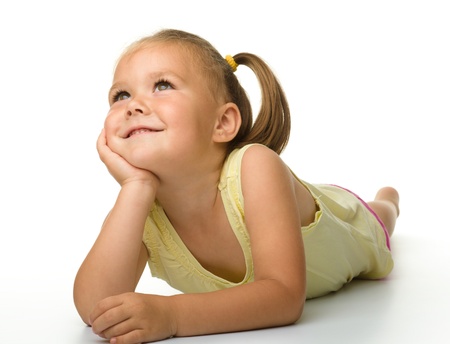 Portrait of a cute happy little girl laying on floor, isolated over whiteの写真素材