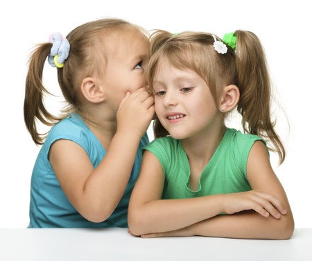 Two little girls are chatting, isolated over whiteの写真素材