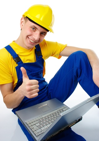 Young construction worker with laptop showing "good" hand sign, isolated over whiteの写真素材