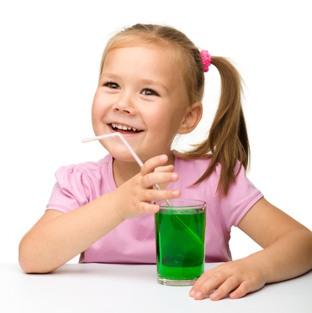 Little girl with a glass of tarragon drink, isolated over whiteの写真素材