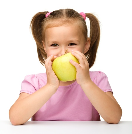 Portrait of a cute little girl with yellow apple, isolated over whiteの写真素材