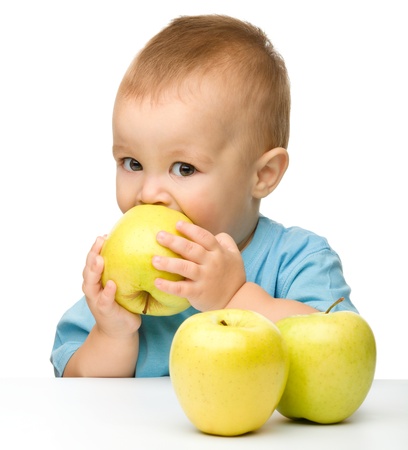 Portrait of a cute little child biting yellow apple, isolated over whiteの写真素材