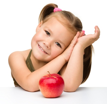 Portrait of a cute little girl with red apple, isolated over whiteの写真素材
