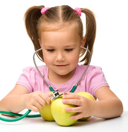 Portrait of a cute little girl with three yellow apples and stethoscope, isolated over whiteの写真素材