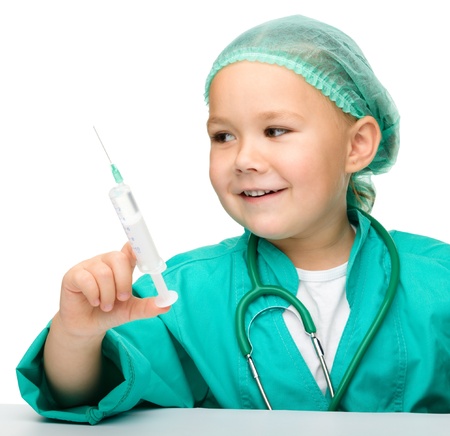 Cute little girl is playing doctor with syringe, isolated over whiteの写真素材