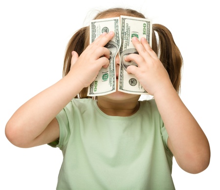 Cute little girl is covering her eyes with dollars, isolated over whiteの写真素材