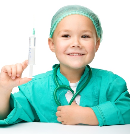 Cute little girl is playing doctor with syringe, isolated over whiteの写真素材