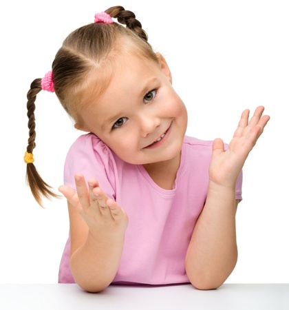 Portrait of a cute little girl sitting at the table, isolated over whiteの写真素材