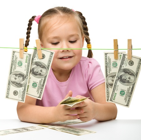 Cute little girl is playing with paper money - dollars, isolated over whiteの写真素材