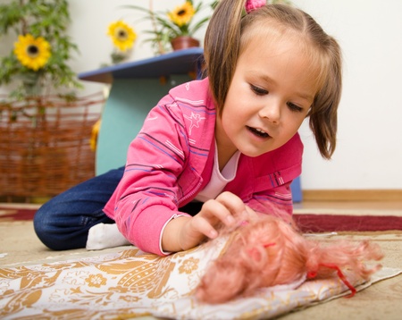 Cute little girl is putting her doll to sleepの写真素材