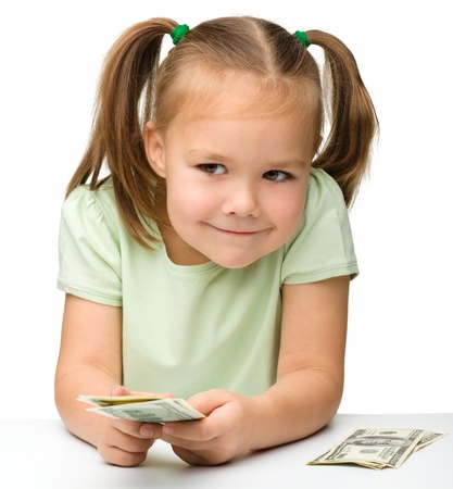 Cute cheerful little girl with paper money - dollars, isolated over whiteの写真素材