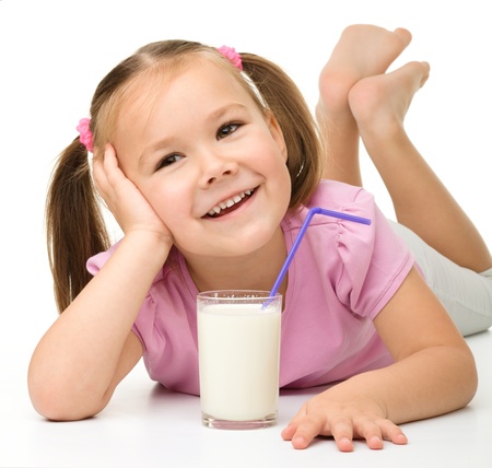 Cute little girl with a glass of milk, isolated over whiteの写真素材