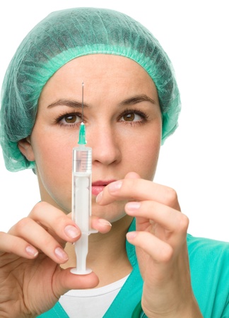 Young nurse is preparing syringe for injection, isolated over whiteの写真素材