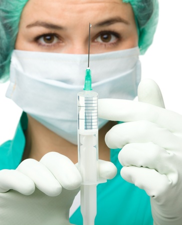 Young nurse is preparing syringe for injection, isolated over whiteの写真素材