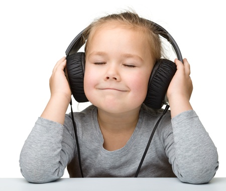 Cute little girl enjoying music using headphones, isolated over whiteの写真素材