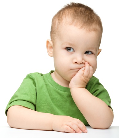 Portrait of a cute and pensive little boy support his head with hand, isolated over whiteの写真素材