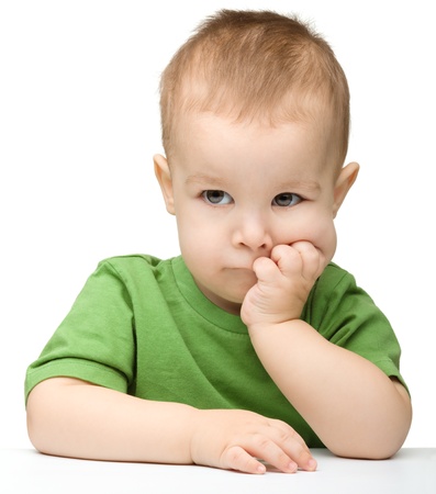 Portrait of a cute and pensive little boy support his head with hands, isolated over whiteの写真素材
