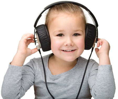 Cute little girl enjoying music using headphones, isolated over whiteの写真素材