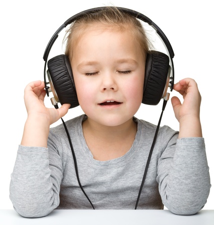 Cute little girl enjoying music using headphones, isolated over whiteの写真素材