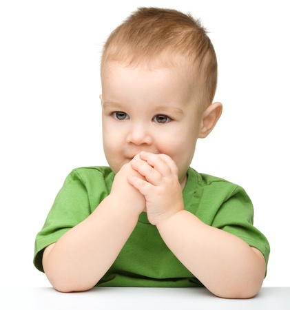 Portrait of a cute and pensive little boy support his head with hand, isolated over whiteの写真素材