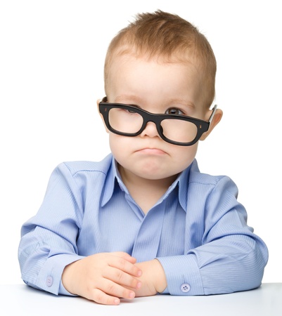 Portrait of a cute little boy wearing glasses and making funny grimace, isolated over whiteの写真素材