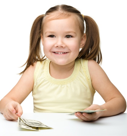 Cute cheerful little girl with paper money - dollars, isolated over whiteの写真素材