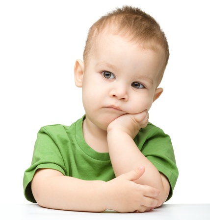 Portrait of a cute and pensive little boy support his head with hand, isolated over whiteの写真素材