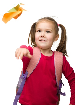 Portrait of little schoolgirl with backpack throwing a paper airplane, isolated over whiteの写真素材