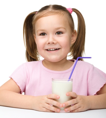 Cute little girl with a glass of milk, isolated over whiteの写真素材