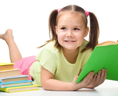 Cute little girl reads a book, isolated over whiteの写真素材