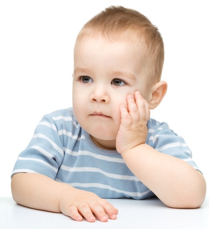 Portrait of a cute and pensive little boy support his head with hand, isolated over whiteの写真素材