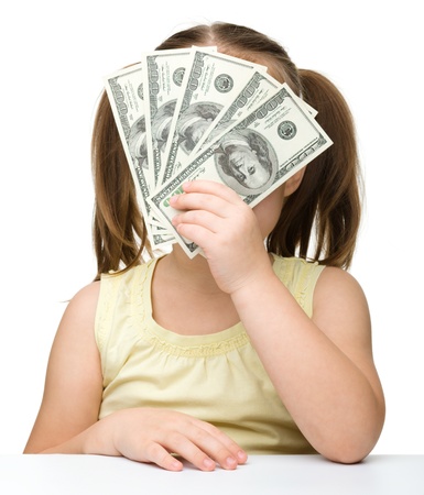 Cute little girl is covering her face with dollars, isolated over whiteの写真素材