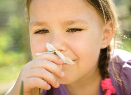 Portrait of a cute little girl smelling flowers outdoorsの写真素材
