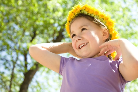 Outdoor portrait of a cute little girl with dandelion wreathの写真素材