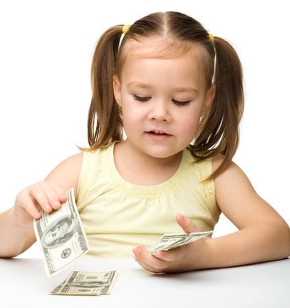 Cute cheerful little girl is counting dollars, isolated over whiteの写真素材