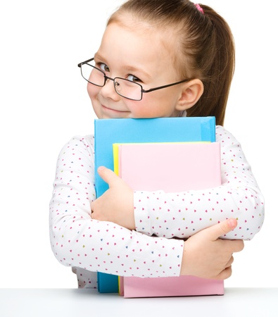 Cute cheerful little girl with books, isolated over whiteの写真素材