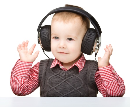 Cute little boy enjoying music using headphones, isolated over whiteの写真素材