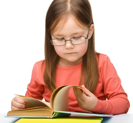 Cute little girl reading book wearing glasses, isolated over whiteの写真素材
