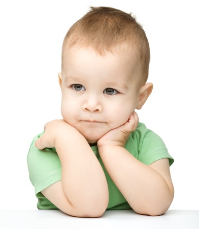 Portrait of a cute and pensive little boy support his head with hand, isolated over whiteの写真素材