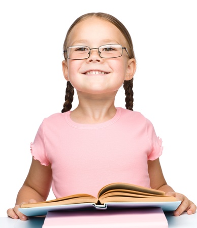 Cute little schoolgirl with a book wearing glasses, isolated over whiteの写真素材
