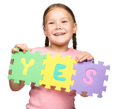 Cute little girl is holding Yes slogan, isolated over whiteの写真素材