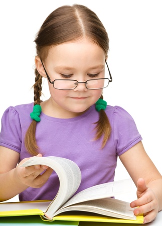 Cute little girl reading book wearing glasses, isolated over whiteの写真素材